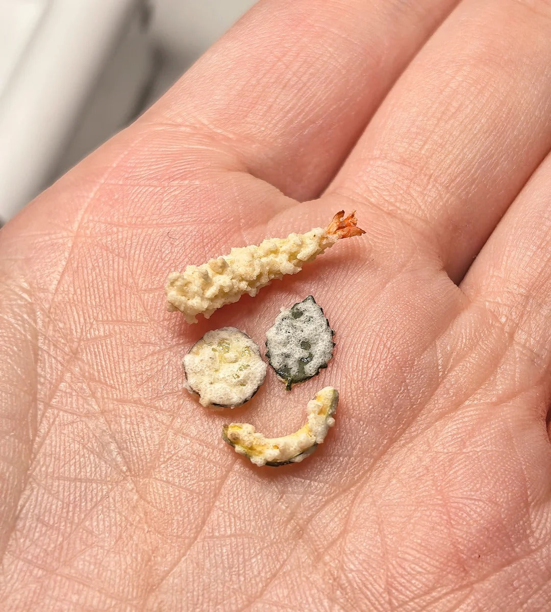 Miniature tempura pieces held in a hand